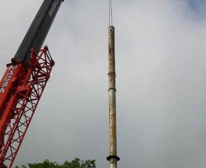 Large piece of scrap metal being lifted high in the air by a crane